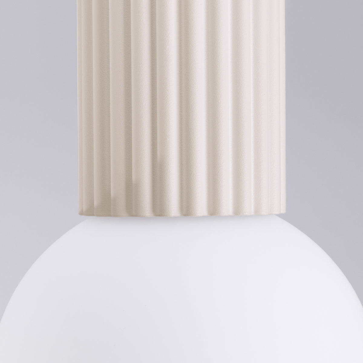 Gros plan du culot cannelé laque beige posé sur la boule de verre opale