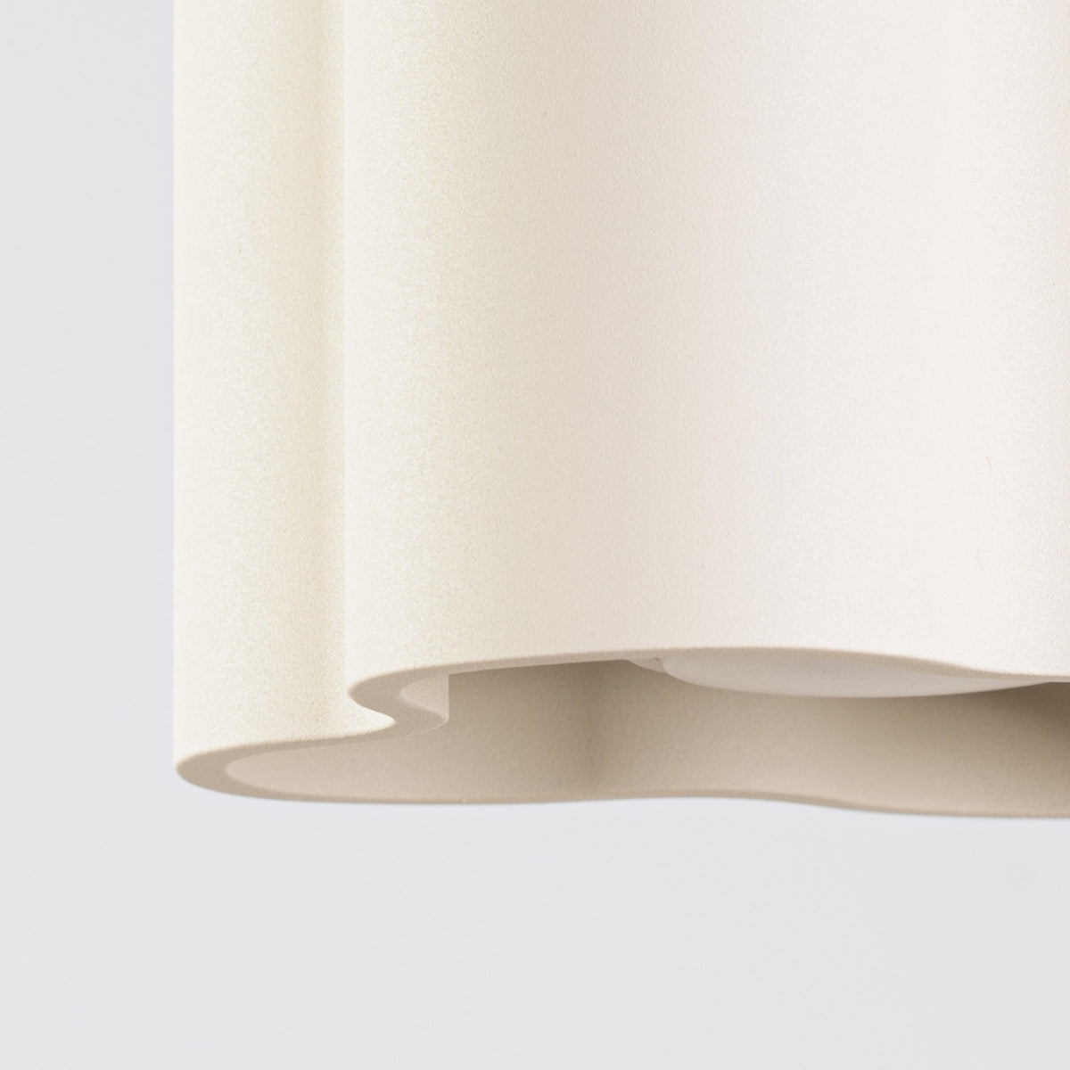 Détail du bord ondulé et de la surface mate du plafonnier Ovio laque beige