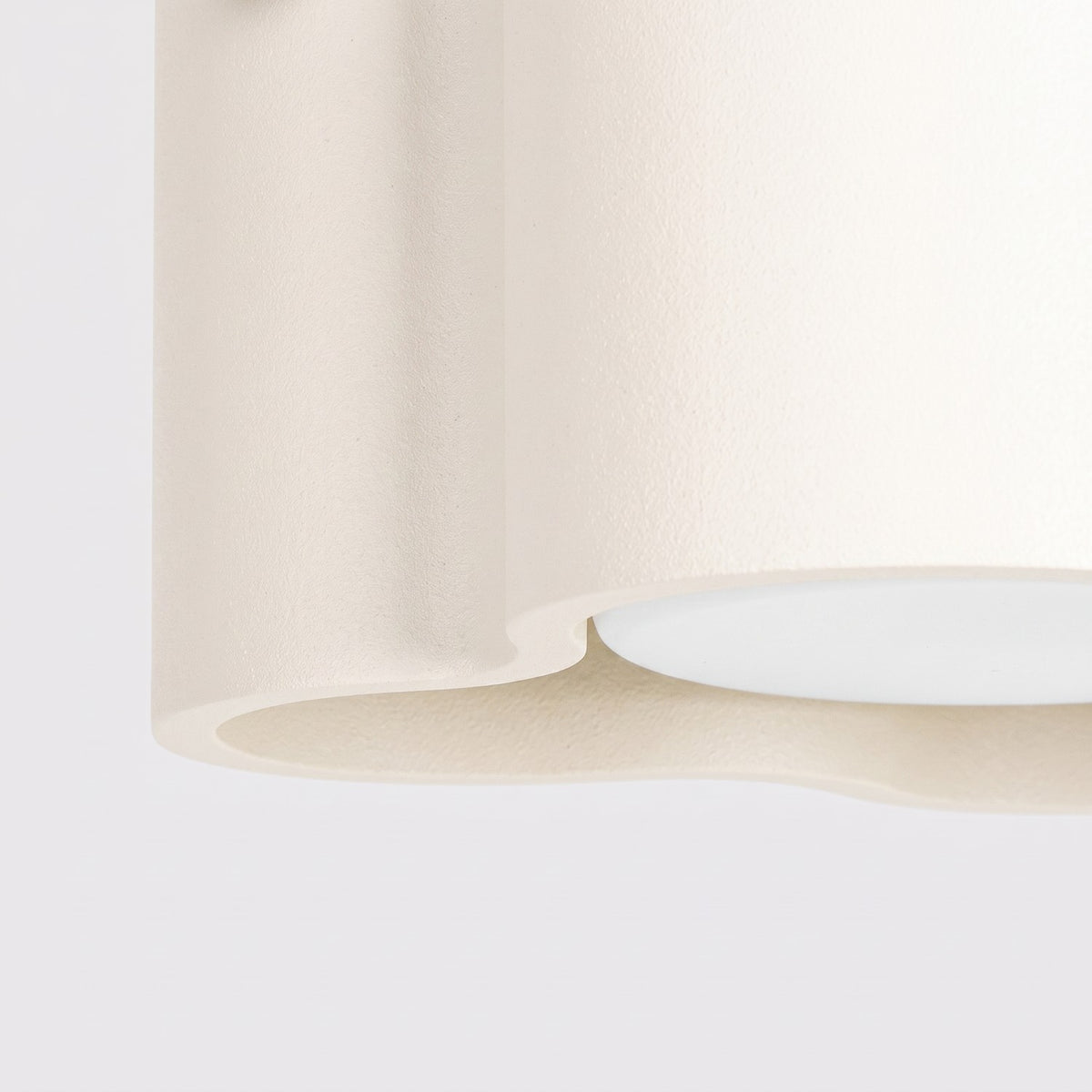 Détail du bord ondulé et de la surface mate du plafonnier Ovio laque beige