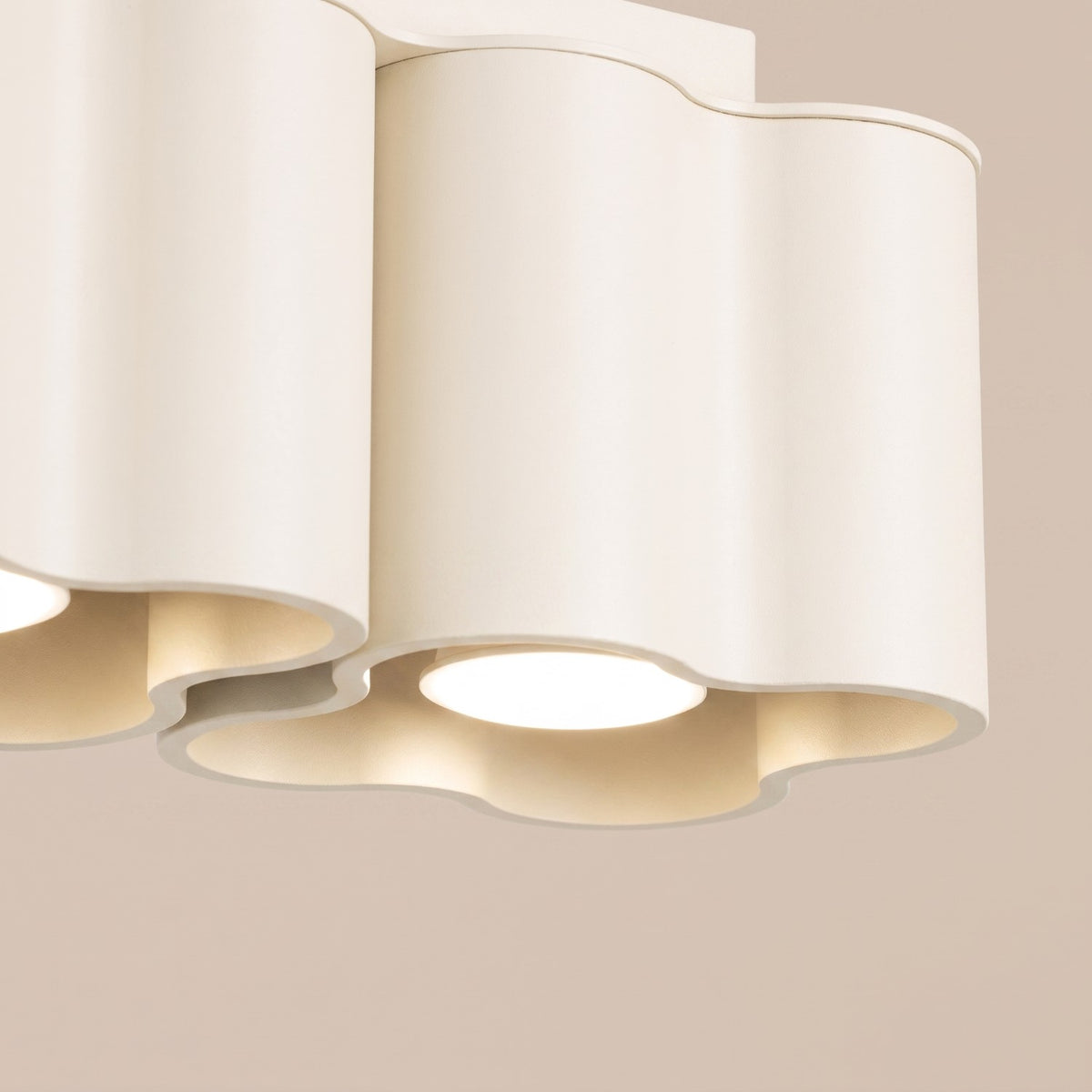 Détail du bord ondulé et d'une ampoule allumée du plafonnier Ovio 2 laque beige
