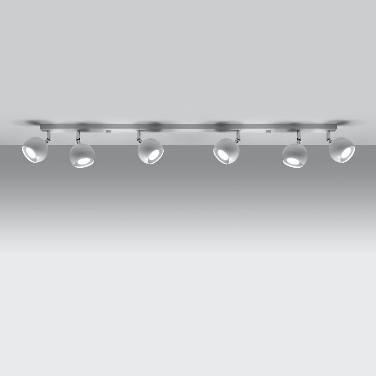 Plafonnier rampe Oculare métal blanc allumé avec ses six spots boule sous un plafond gris