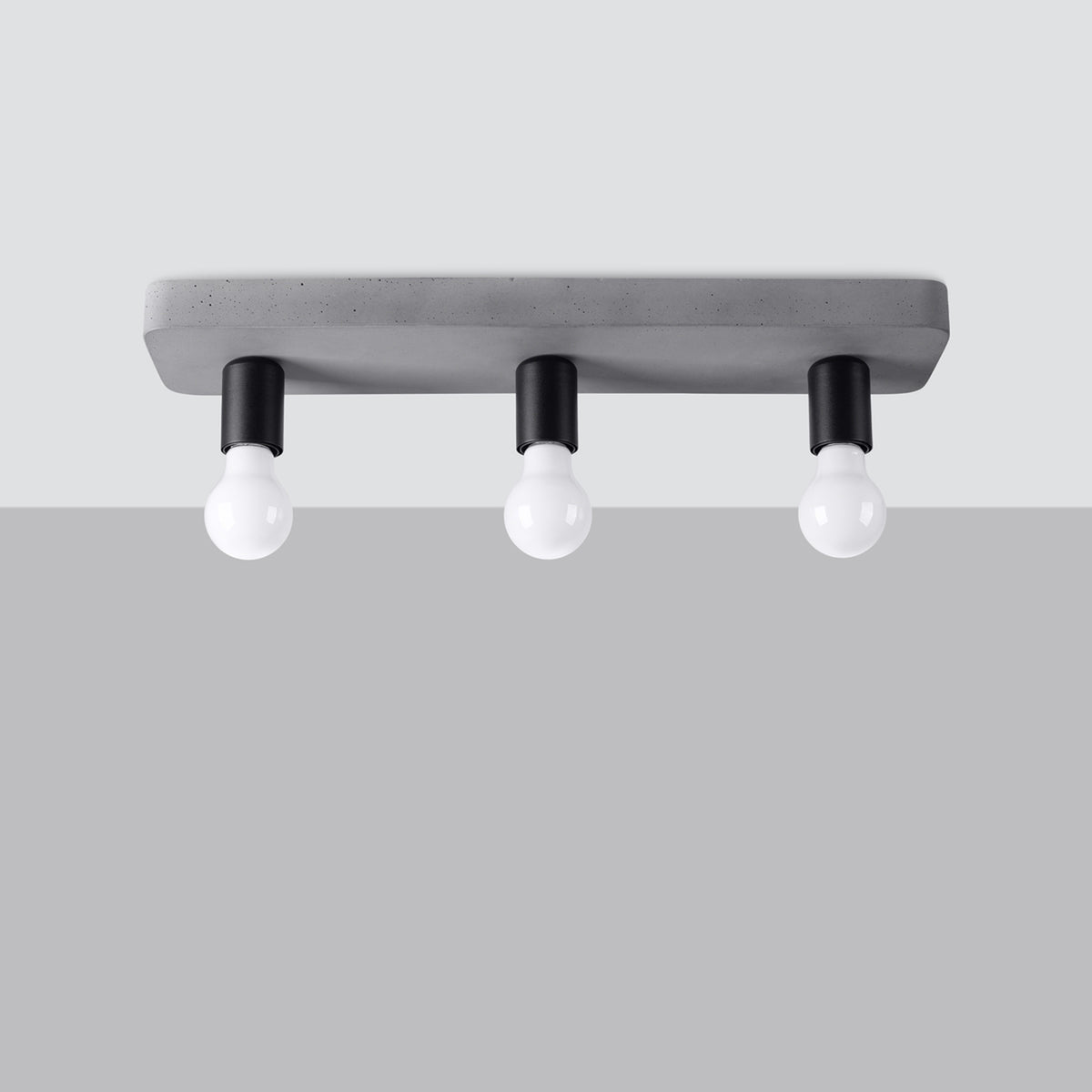 Plafonnier Tavo en béton gris à trois douilles noires sur fond gris