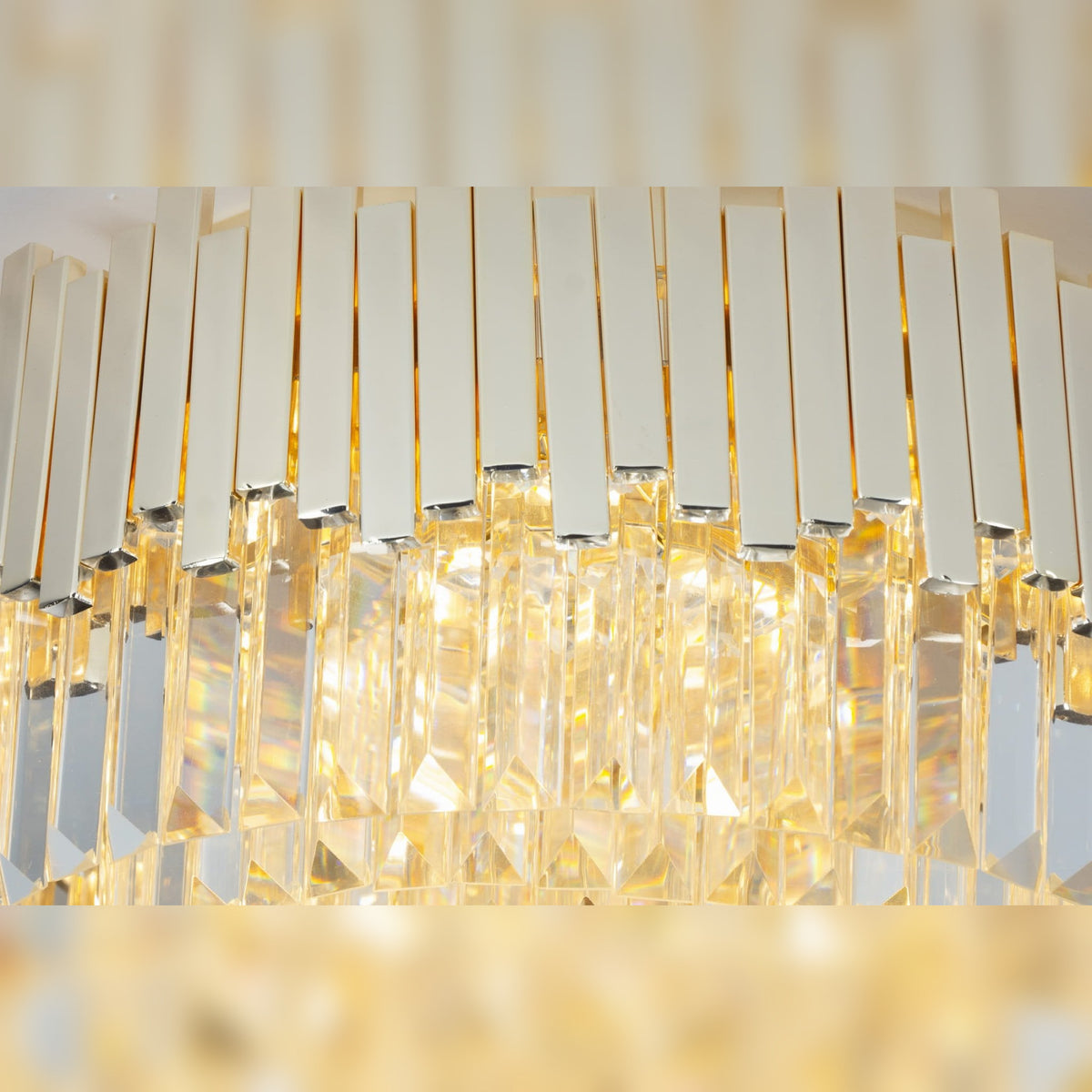 Détail des barrettes en métal doré brillant et des prismes de verre taillés du plafonnier Trend allumé