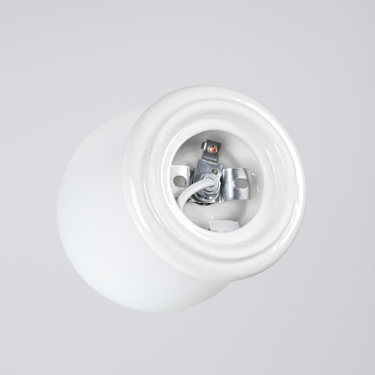 Intérieur du socle en céramique émaillée blanche du plafonnier Zori avec sa patte de fixation et son câble