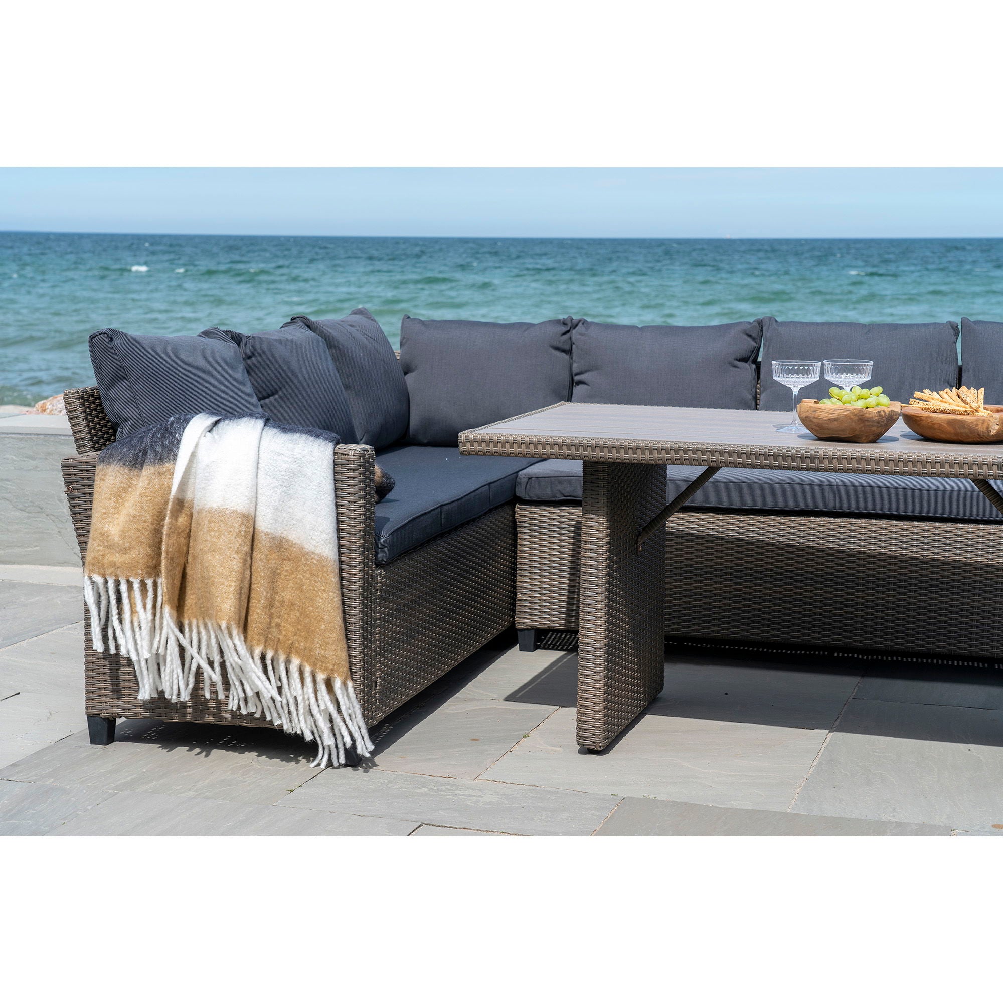 Plaid Sintra laine rayé noir blanc camel drapé sur salon de jardin en rotin bord de mer