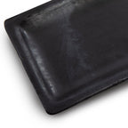 Gros plan sur l'angle arrondi et le bord relevé du plat à sushis 25 x 12 cm aux nuances grises