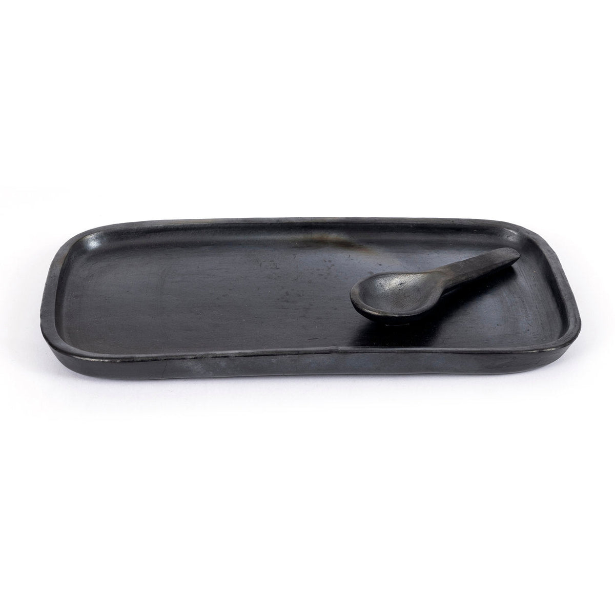 Plat à tapas en terre cuite noircie avec une petite cuillère noire posée dessus