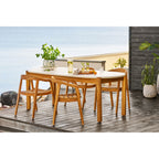 Table de terrasse dressée avec cache-pot posé sur le plateau floral et chaises en bois
