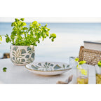 Plateau floral en céramique sur une table blanche à côté d'un cache-pot garni de basilic