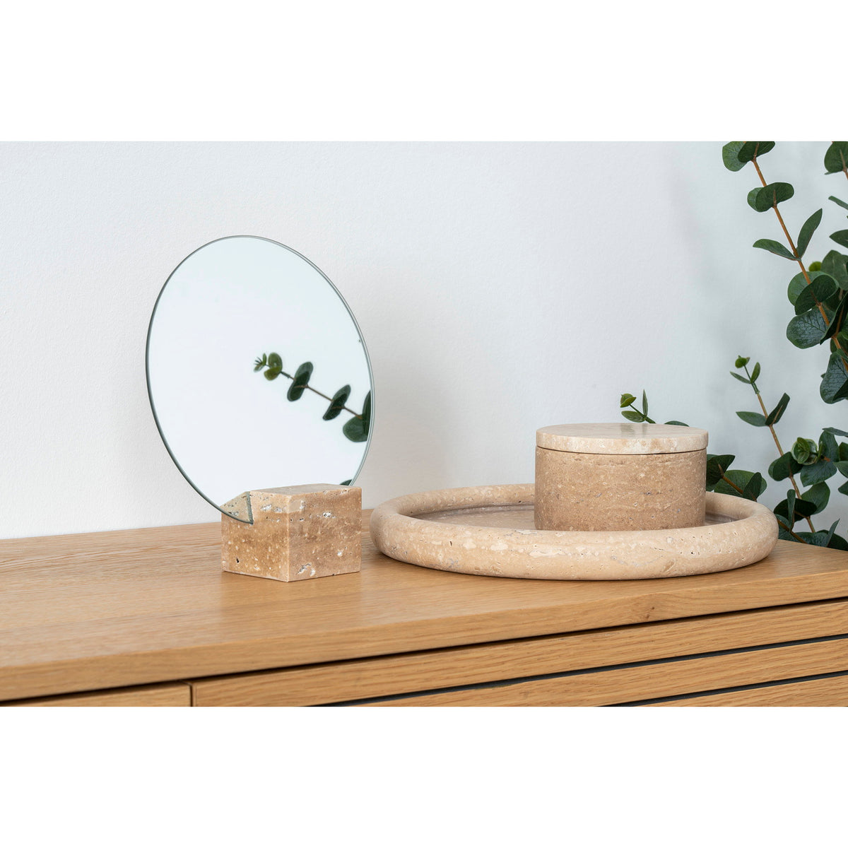 Plateau en travertin posé sur un buffet en chêne avec une boîte ronde assortie et un miroir sur socle