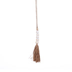 Pompon décoratif Cone suspendu à son cordon avec cinq coquillages blancs empilés et une jupe de fibres végétales sur fond blanc
