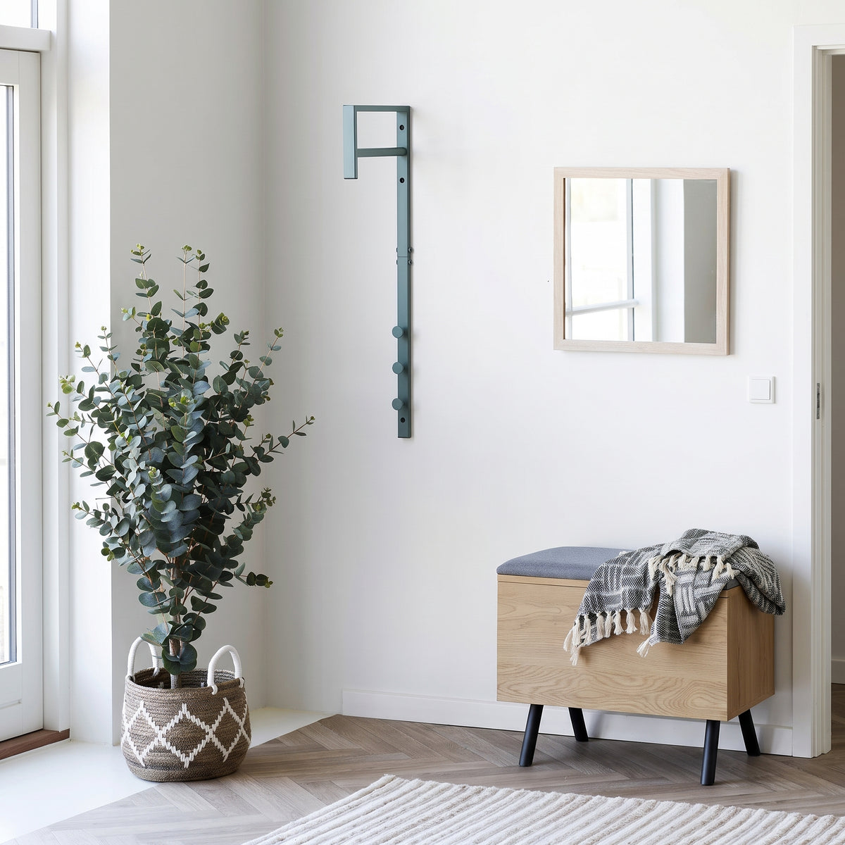 Porte-manteau Trento vert sauge dans une entrée claire, près d'un banc coffre en bois et d'un eucalyptus