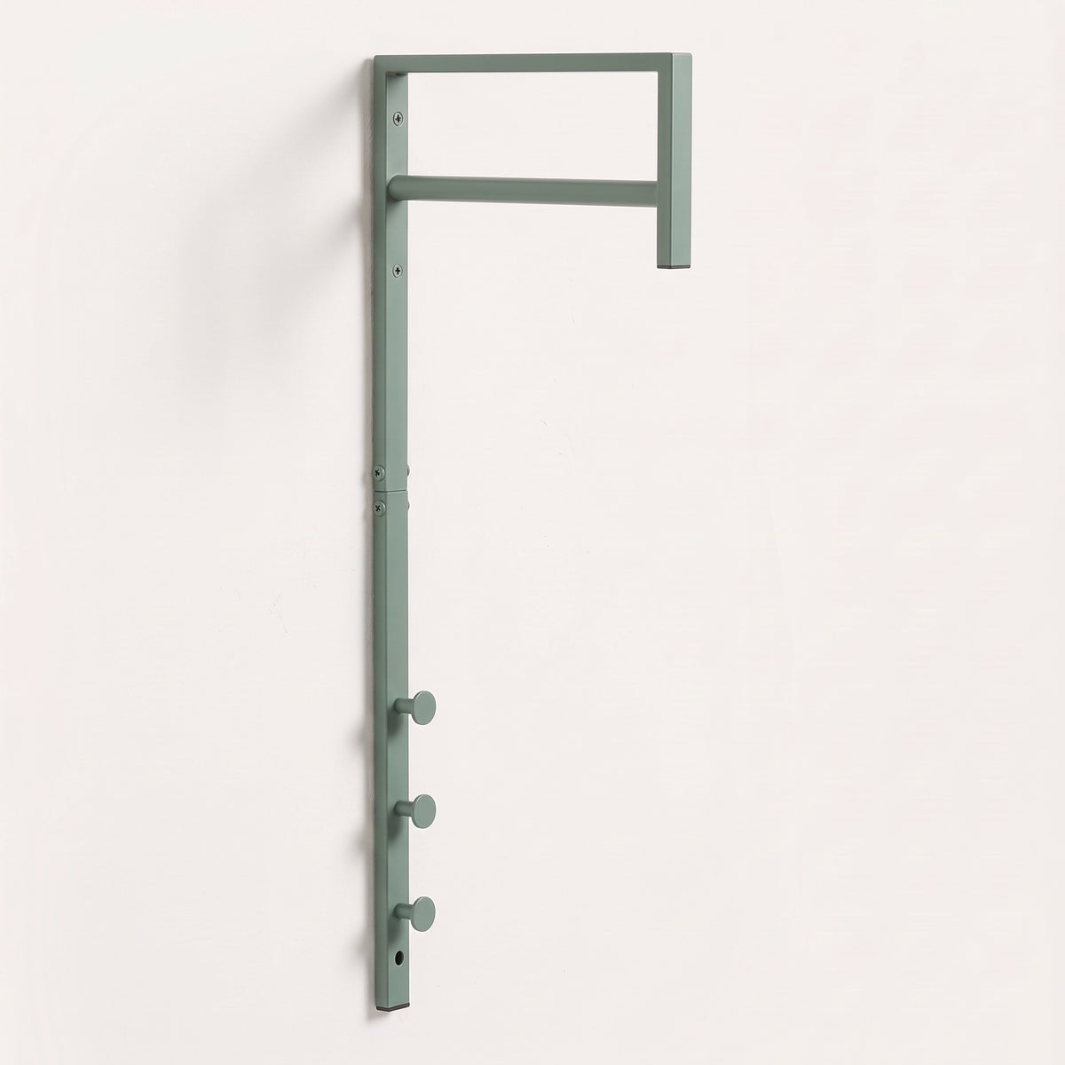 Porte-manteau mural Trento en métal vert sauge sur mur blanc, avec sa barre de penderie et ses trois crochets ronds