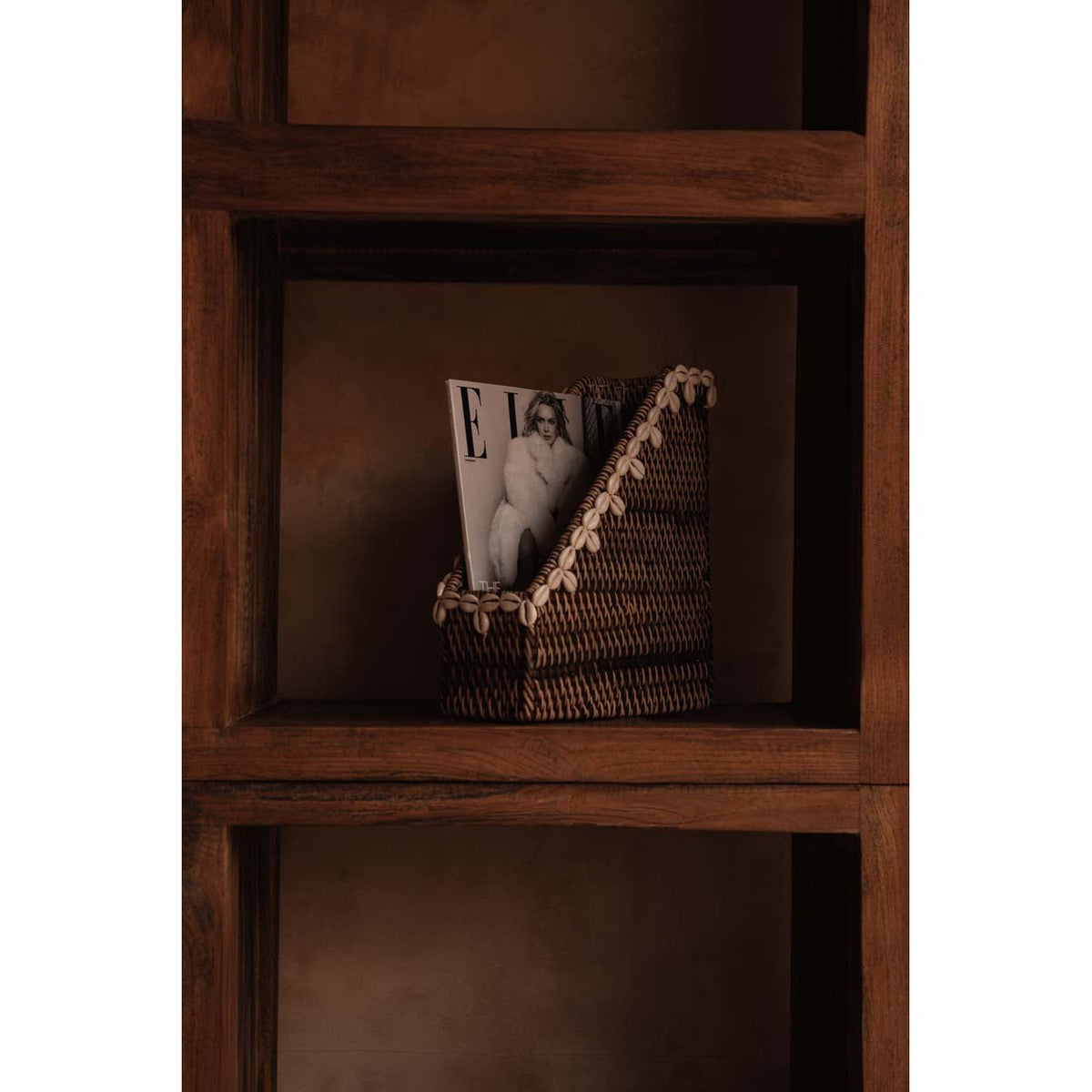 Porte-revues en rotin avec un magazine dans une case de bibliothèque en bois