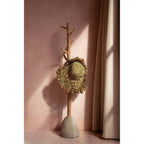 Portemanteau en teck et béton portant un chapeau de paille à franges contre un mur rose
