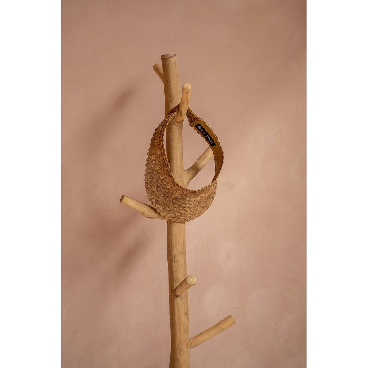 Haut du tronc de teck du portemanteau avec une visière tressée accrochée à une branche