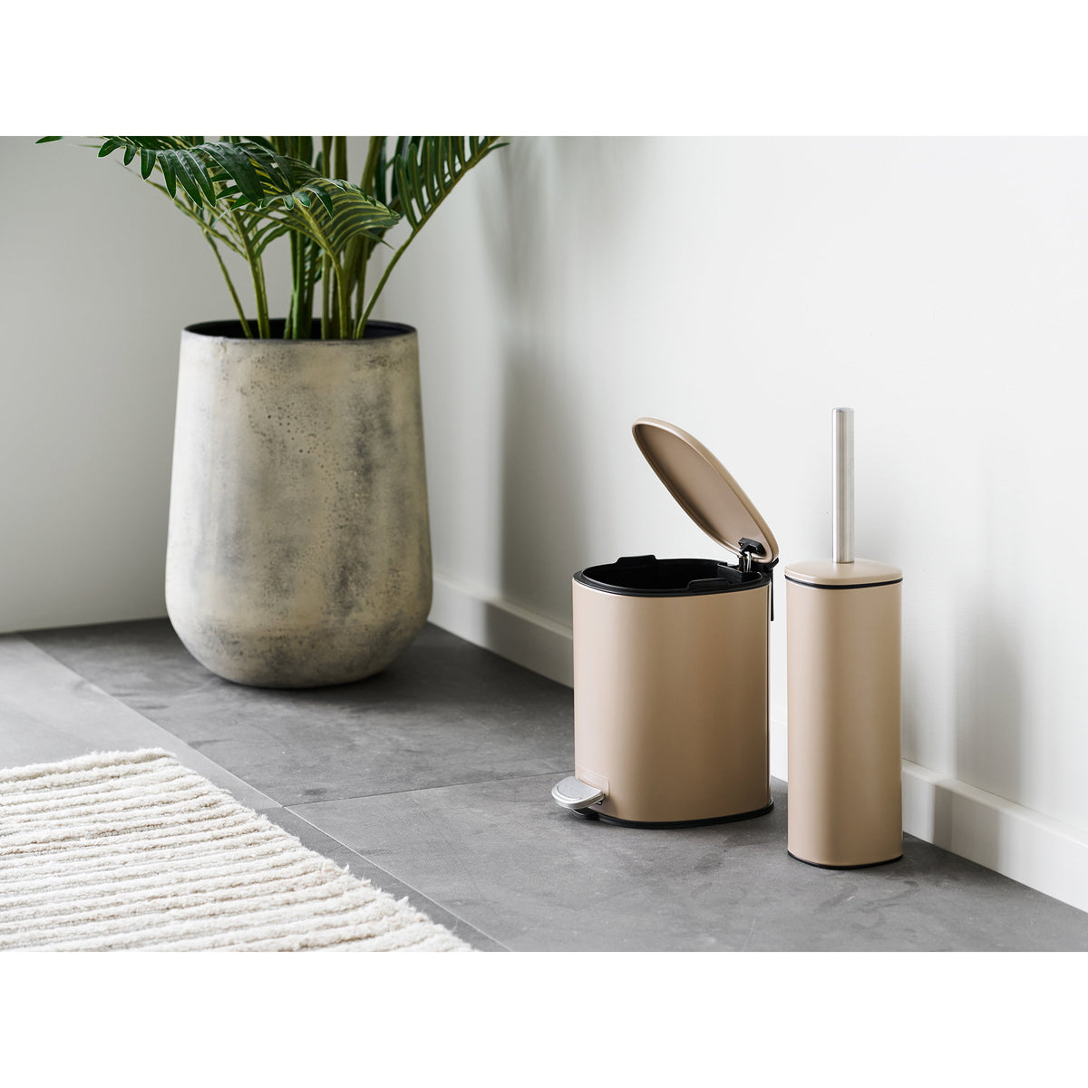 Poubelle à pédale Lodi beige couvercle ouvert dans une salle de bain à côté d'une brosse de toilette assortie