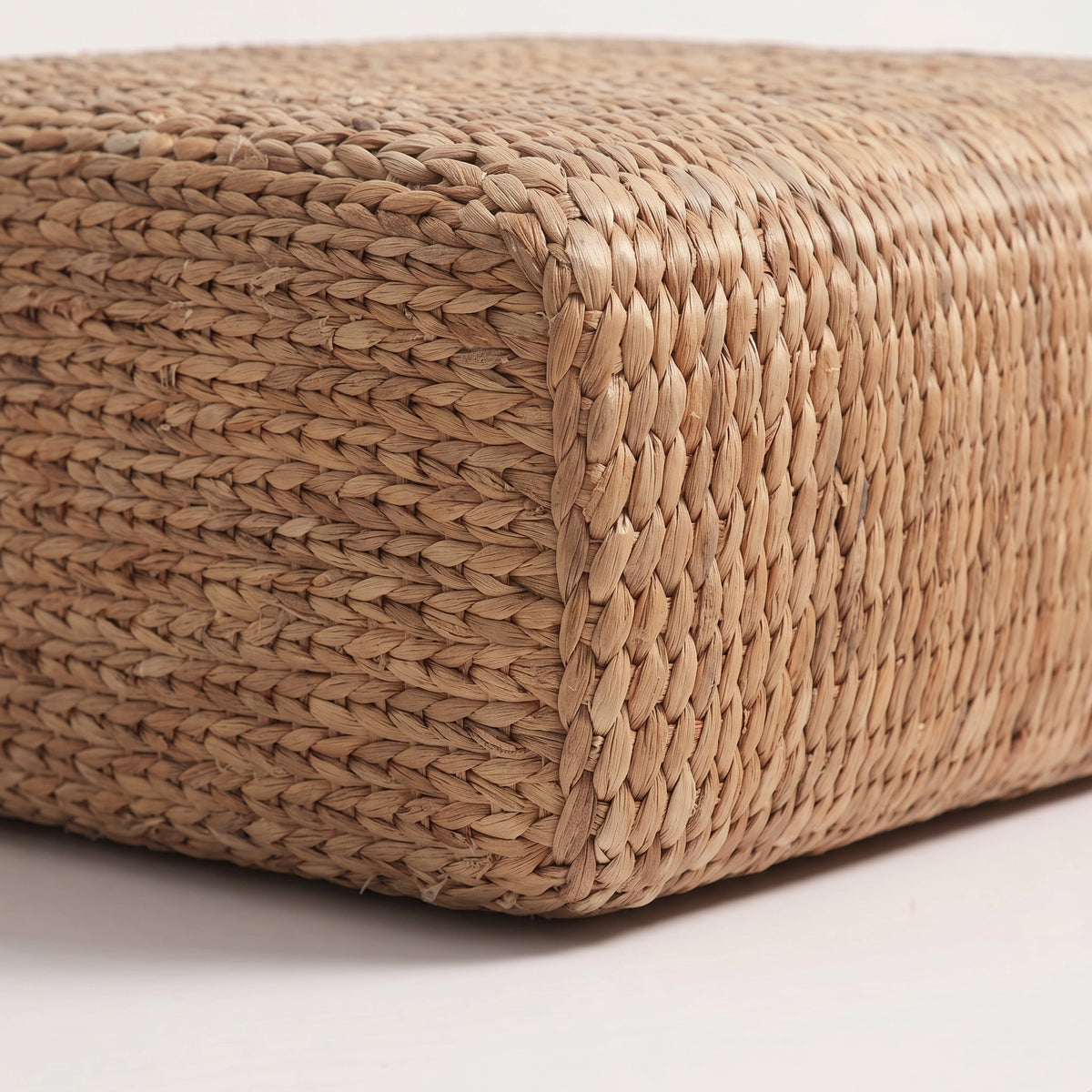 Gros plan sur le tressage en jacinthe d'eau naturelle et l'angle arrondi du pouf carré