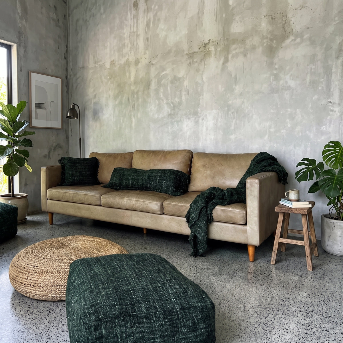Pouf carré Oh My Gee en coton tissé vert forêt devant un canapé en cuir clair, près d'un pouf rond tressé, dans un salon aux murs en béton