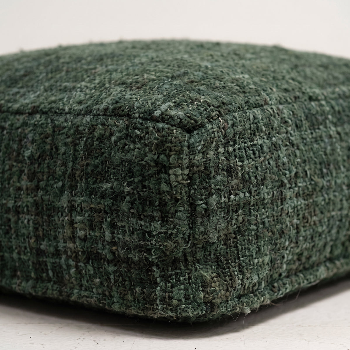 Gros plan sur le coton tissé vert forêt aux fils de plusieurs verts et sur l'arête cousue du pouf Oh My Gee
