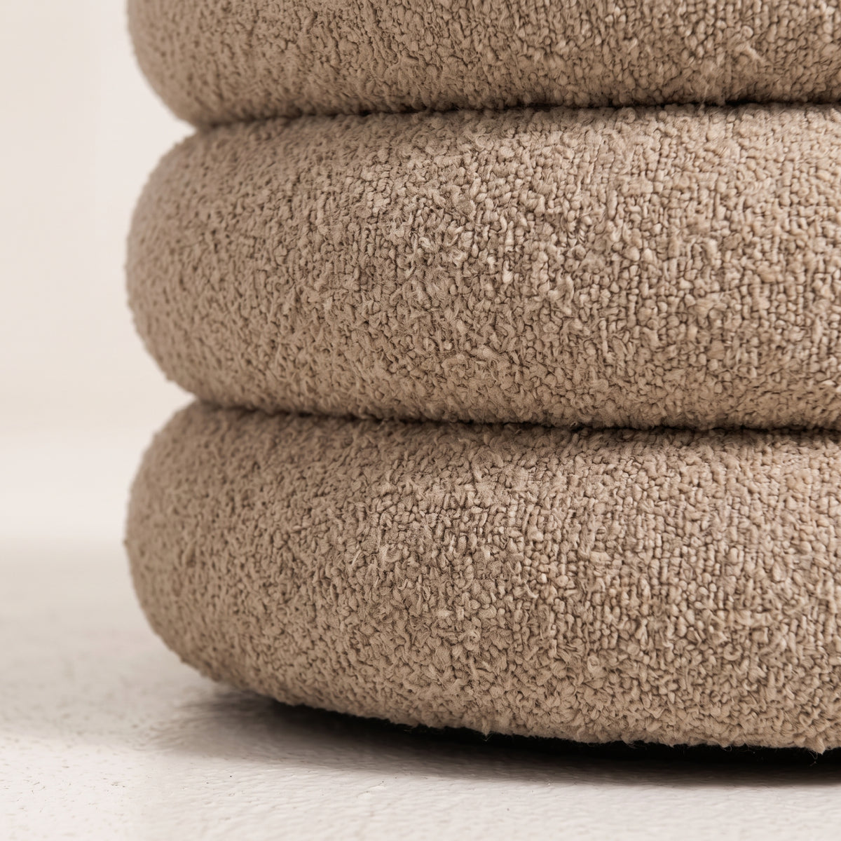 Gros plan de la texture bouclée beige des bourrelets du pouf