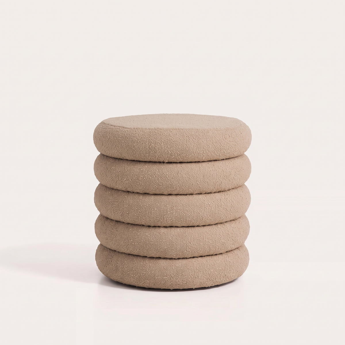 Pouf coffre rond en bouclé beige à cinq bourrelets sur fond blanc
