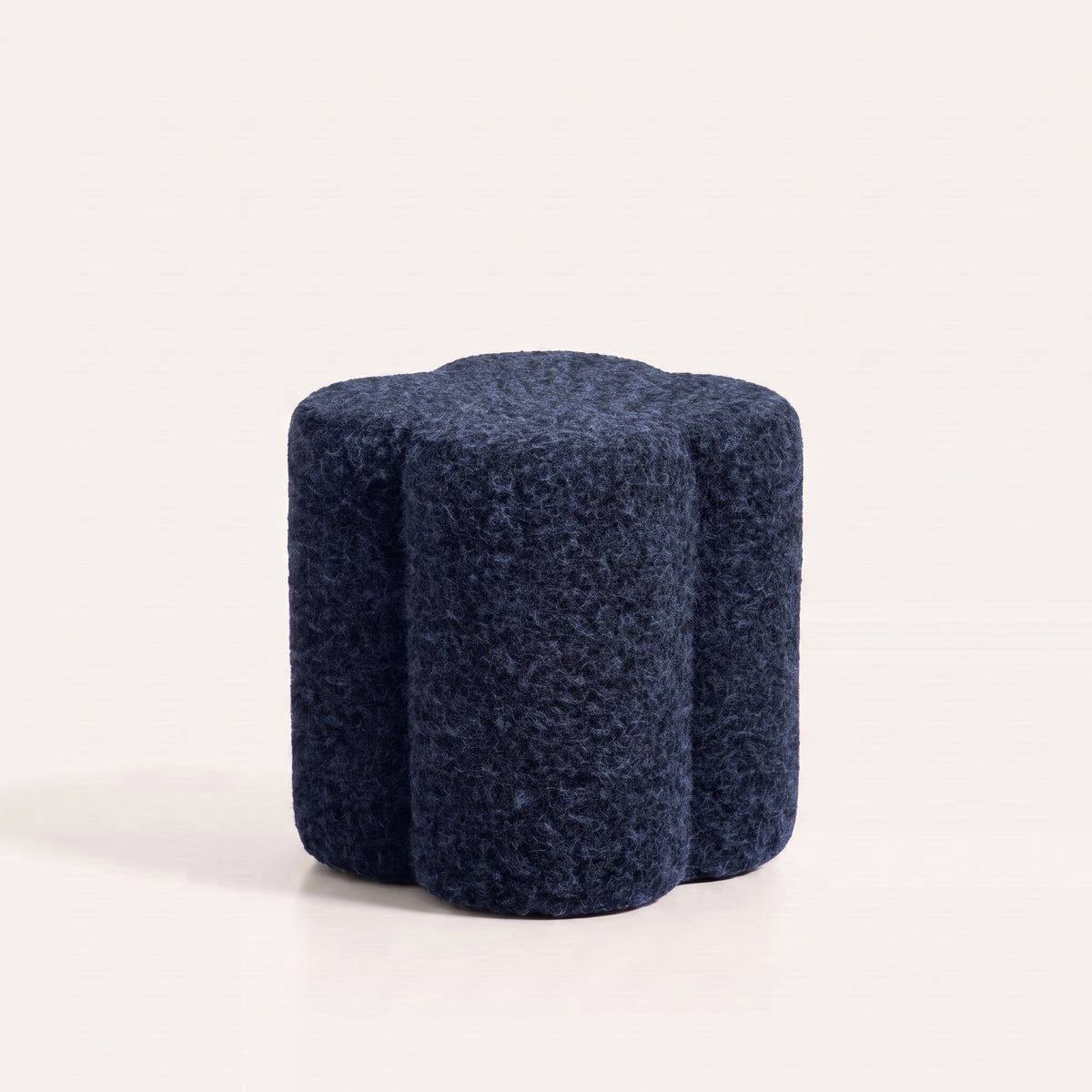 Pouf Durban en tissu bouclé bleu marine à quatre lobes arrondis, vu sur fond blanc