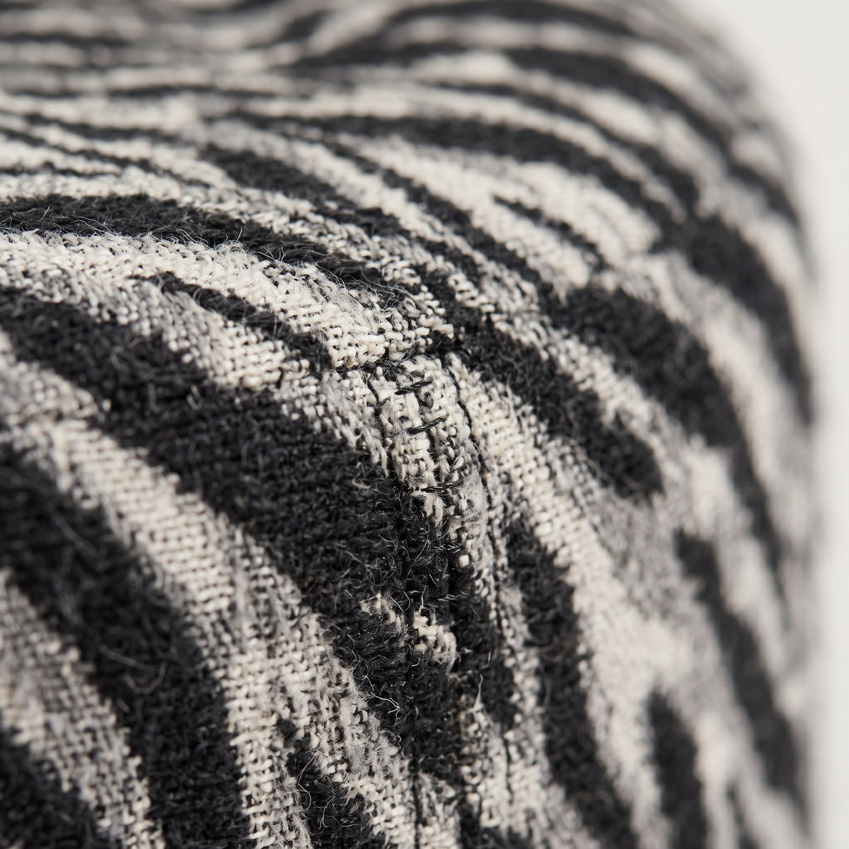 Gros plan du tissage jacquard noir et blanc cassé et de la couture du pouf