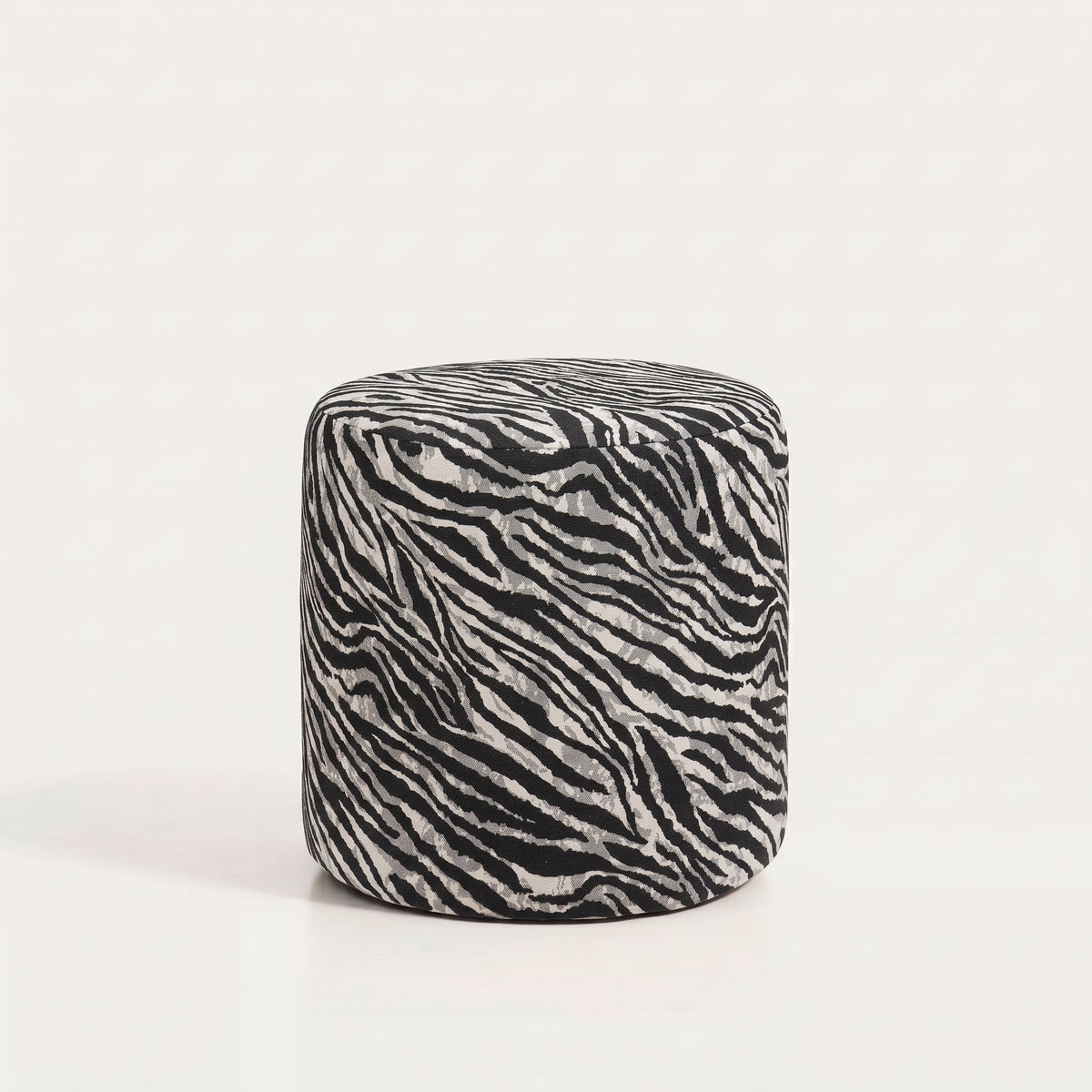 Pouf cylindrique en jacquard zébré noir et blanc cassé sur fond blanc