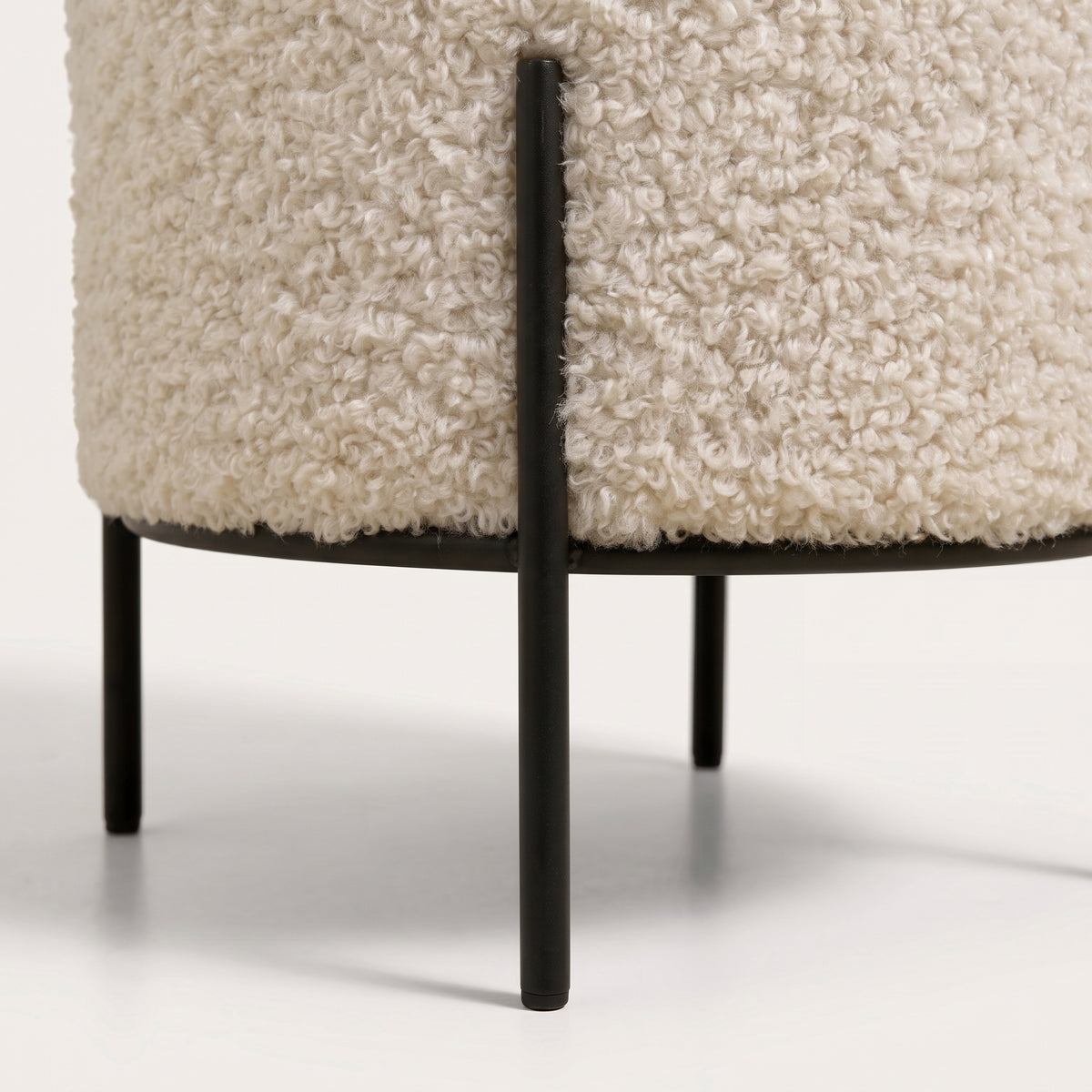 Détail de la bouclette crème et des pieds en acier noir reliés par un cercle sous l'assise du pouf Alford