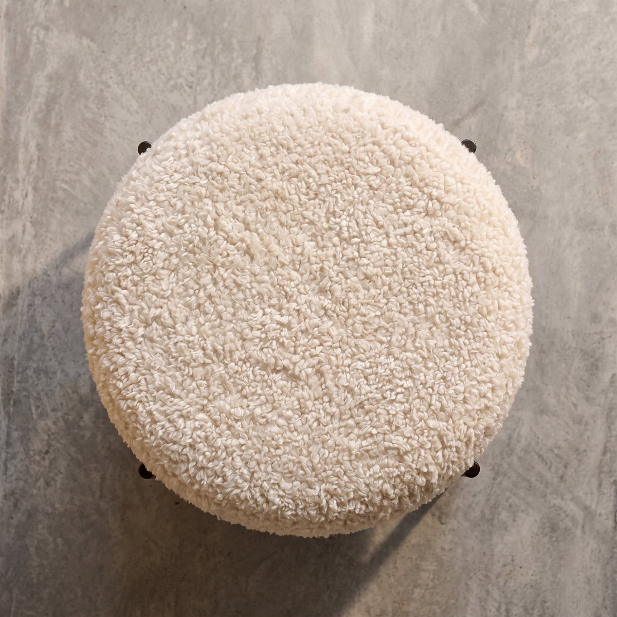 Assise en bouclette crème du pouf rond Alford, vue de dessus sur un sol en béton