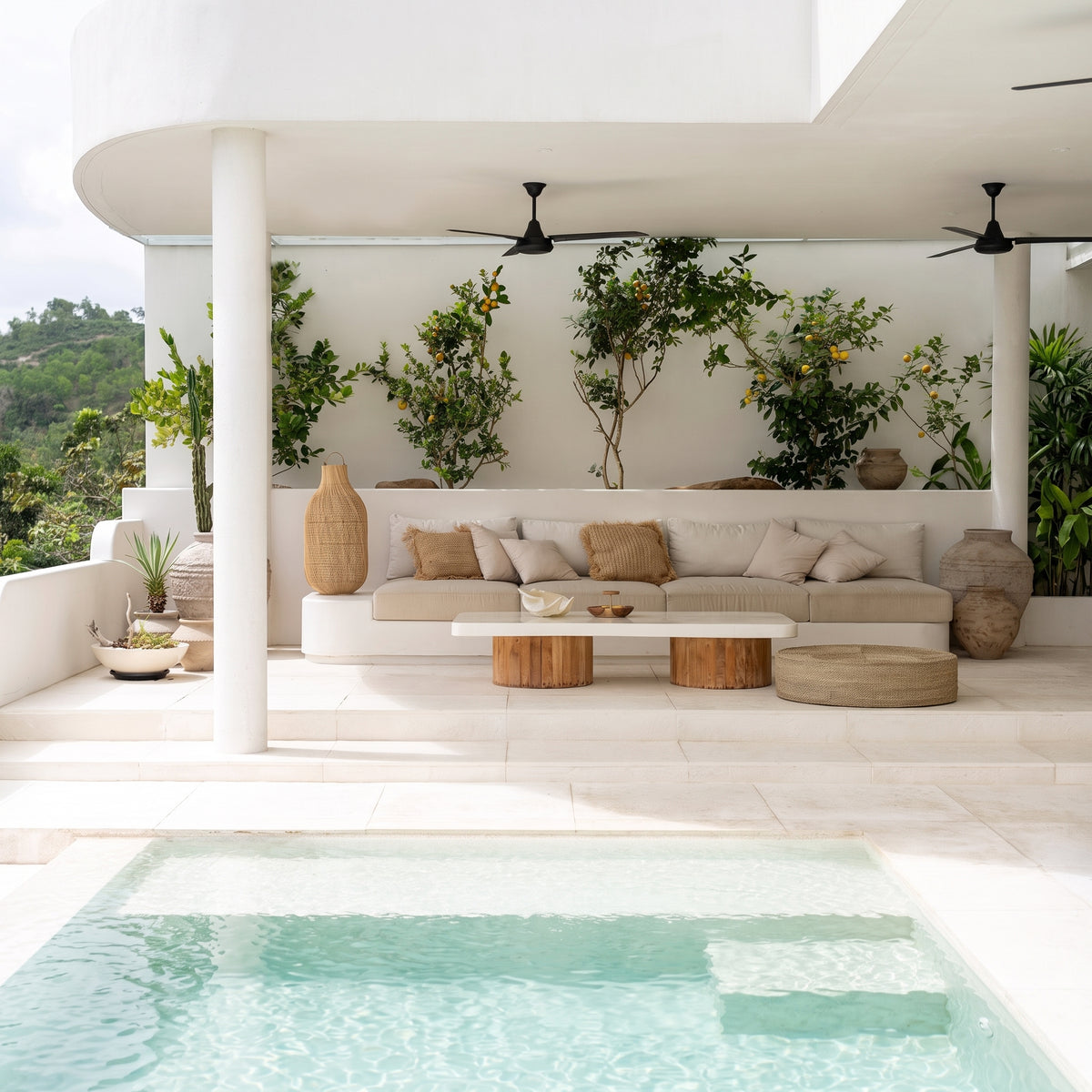 Pouf bas en jonc de mer sur une terrasse blanche au bord d'une piscine, près d'une banquette et d'une table basse