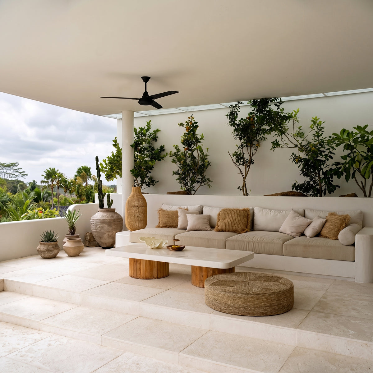 Pouf rond en jonc de mer sur une terrasse couverte, à côté d'une table basse blanche et d'une banquette beige