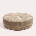 Grand pouf rond bas en jonc de mer tressé naturel sur fond blanc