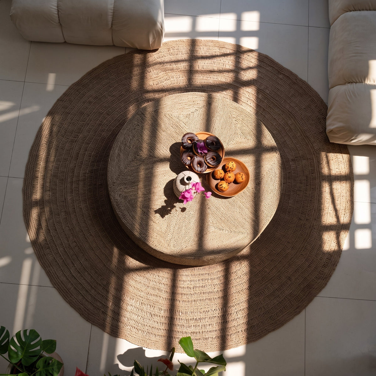 Pouf rond en jonc de mer vu d'en haut, centré sur un tapis rond en jute, avec deux plateaux posés dessus