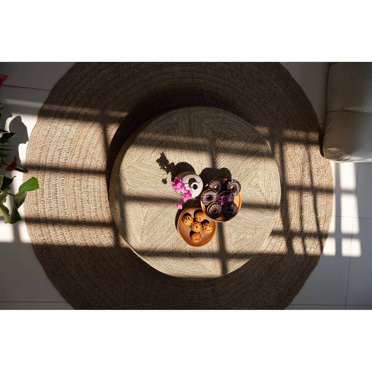 Pouf rond en jonc de mer vu du dessus au centre d'un grand tapis rond tressé