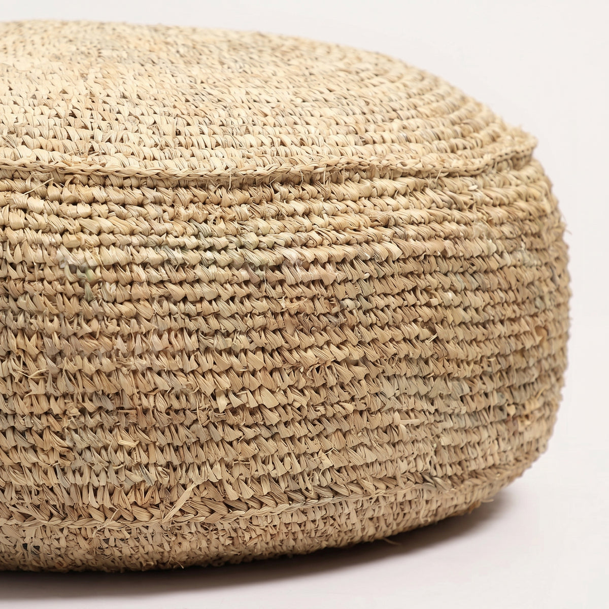 Gros plan sur les mailles en raphia naturel crocheté du pouf rond Flores