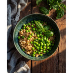 Saladier Aqua vert profond garni de céréales aux petits pois et au basilic sur une table en bois