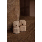 Salière et poivrière Sumba en pierre de grès sur une table en bois près d'un vase en terre