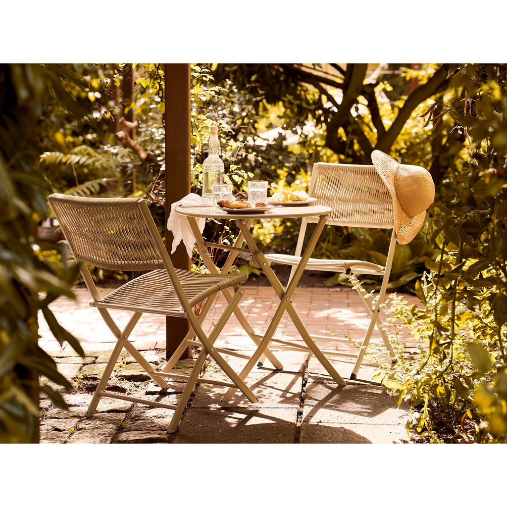 Salon bistro Arcas taupe dans jardin vert estival avec croissants et chapeau de paille