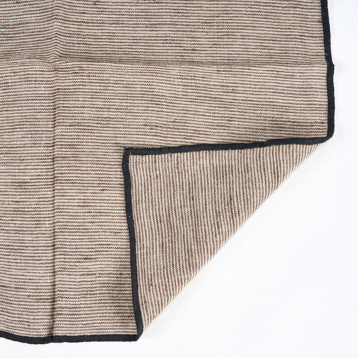 Coin replié de la serviette Code montrant l'envers de la toile rayée et la bordure noire