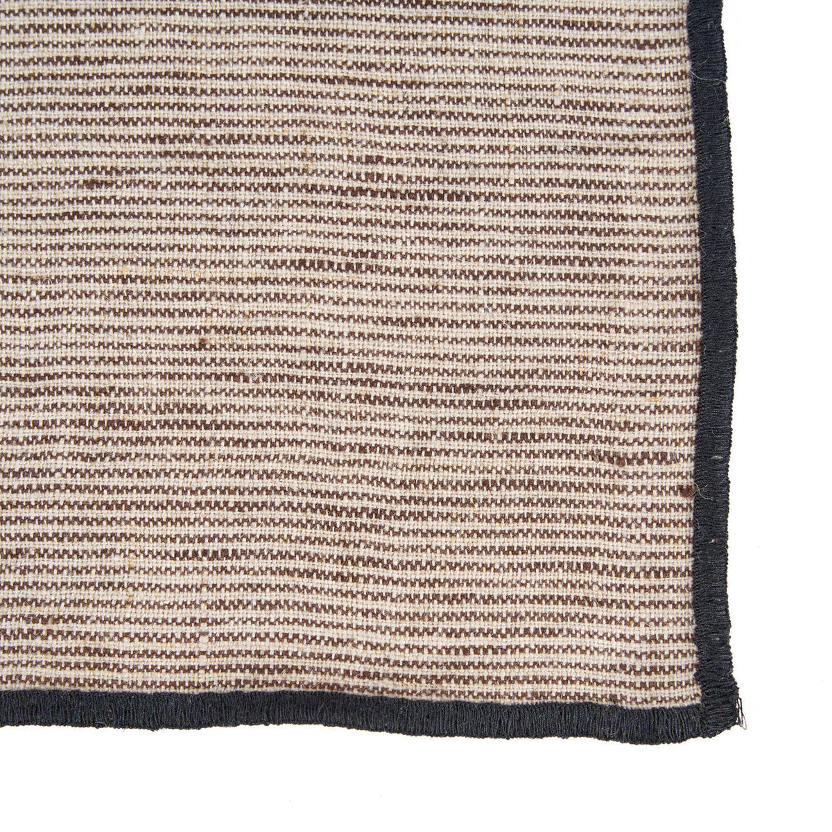 Gros plan sur le tissage rayé en lin de la serviette Code et sa bordure noire cousue