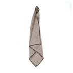 Serviette de table Code en lin naturel pliée en pointe avec sa bordure noire