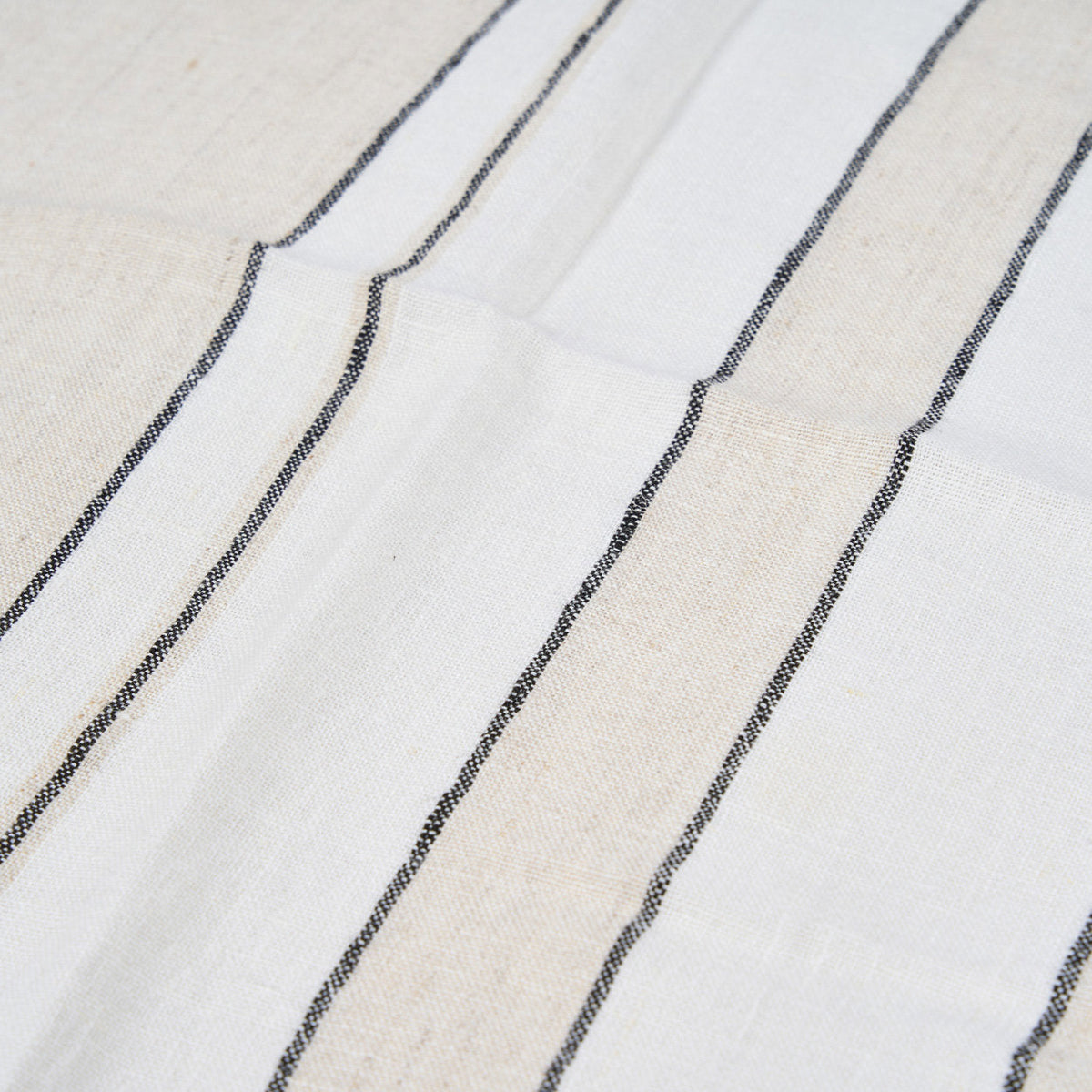 Détail du tissage en lin blanc et des bandes naturelles bordées de rayures noires de la serviette Provence
