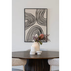 Bougeoirs en ciment gris clair avec une bougie pilier allumée à côté d'un vase garni sur une table ronde en bois foncé