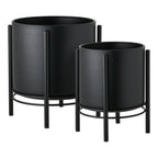 Les deux cache-pots en acier noir sur leur support filaire vus de trois quarts