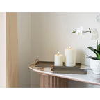 Plateaux en acier taupe sur une console en marbre avec deux bougies blanches et une orchidée