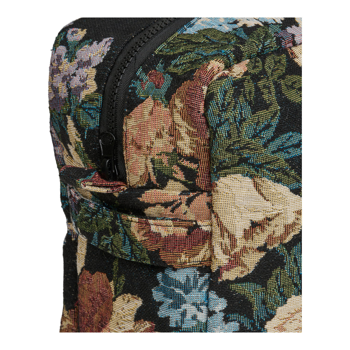 Gros plan sur les fleurs tissées et sur la fermeture à glissière noire d'une trousse Zoe