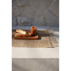 Set de table Isey posé sur un banc de pierre au soleil avec un plateau en teck et un oeuf à la coque