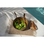 Set de table Isey vu de dessus avec un saladier en grès des couverts à salade en bois et du pain grillé